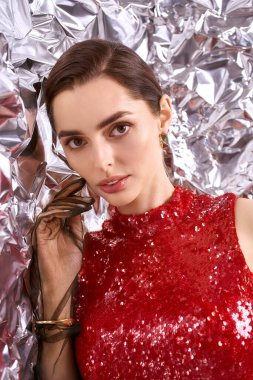 Göz kamaştırıcı kırmızı elbiseli genç bir kadın neşeli, ışıl ışıl bir sahnede parıldıyor..