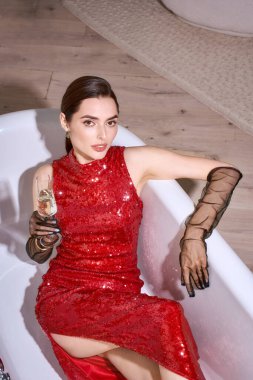 Çarpıcı kırmızı elbiseli genç bir kadın sıcak ve neşeli bir atmosferde kutlamanın tadını çıkarıyor..