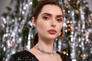 Genç bir kadın, arkaplandaki parlak tatil ışıklarına karşı şenlikli bir kıyafetle güzellik saçıyor..