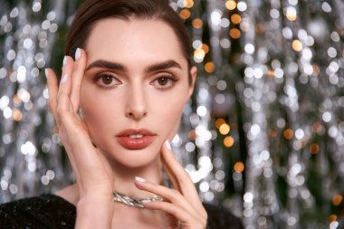 Güzel genç bir kadın, etrafındaki parıldayan ışıklarla şenlikli bir atmosferin tadını çıkarıyor..