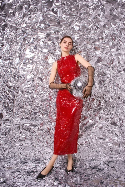 Canlı kırmızı elbiseli hoş bir genç kadın neşeli bir kutlamanın tadını çıkarıyor. Etrafı şenlikli dekorlarla çevrili..