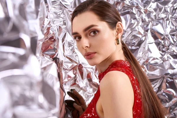 Şenlikli atmosfer, pırıl pırıl kırmızı elbiseli, neşe saçan güzel bir genç kadını sarıyor..