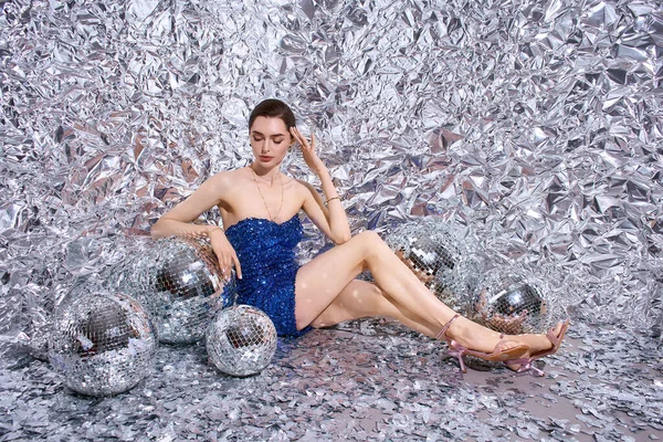 Mavi pullu elbiseli genç kadın parlayan disko balolarının arasında rahatlıyor, neşeyle kutluyor..