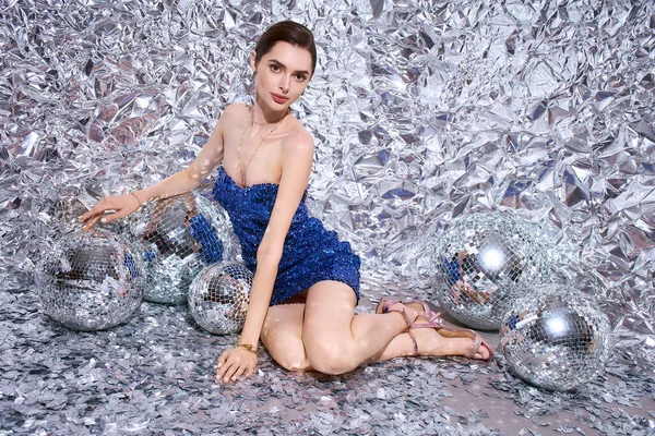 Genç bir kadın ışıltılı bir kutlama atmosferinde göz kamaştırıcı bir kıyafet giyer..