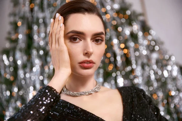 Genç bir kadın ışıltılı süslemelerle çevrili, şen şakrak bir elbiseyle parlıyor..