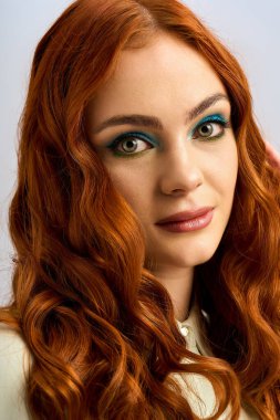 Bu hayat dolu genç kadın yaratıcı bir stüdyoda çarpıcı kızıl saçlarını ve göz makyajını sergiliyor..