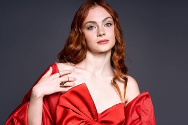 Kızıl saçlı genç bir kadın şık kırmızı bir fiyonkta tatil neşesi sergiliyor.