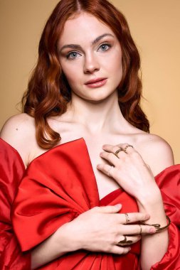 Canlı kızıl saçlı genç bir kadın tatil sezonunu kutlarken koyu kırmızı bir fiyonk sergiliyor..