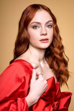 Kızıl saçlı genç bir kadın çarpıcı kırmızı bir fiyonkta zarifçe poz veriyor..