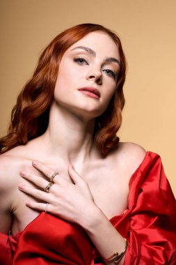 Çarpıcı kızıl saçlı genç bir kadın güzel kırmızı bir fiyonkla tatil modasını sergiliyor..