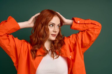 Turuncu gömlekli genç bir kızıl zarif poz verir, sonbahar tarzının özünü yakalar..