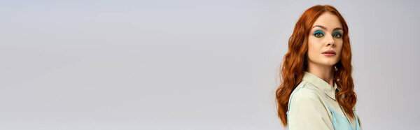 Живая молодая женщина с рыжими волосами уверенно позирует, подчеркивая ее смелый макияж артистизм, баннер