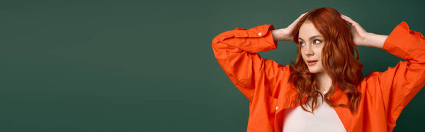 A young woman with red hair poses confidently in an orange shirt reflecting autumn trends, banner