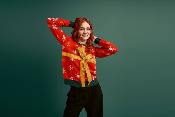 Веселая молодая женщина улыбается в своем рождественском свитере, готовая к зимнему веселью.
