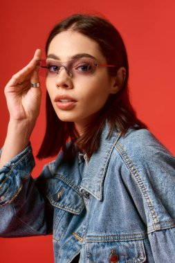 Şık bir genç kadın, kot tarzını stüdyoda sergiliyor, kendine güveni tam..