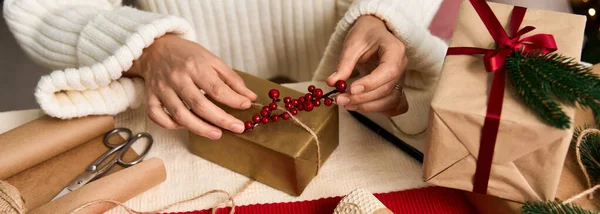 Hands carefully embellish a wrapped present with festive decor, preparing for Christmas cheer. — Stock Photo