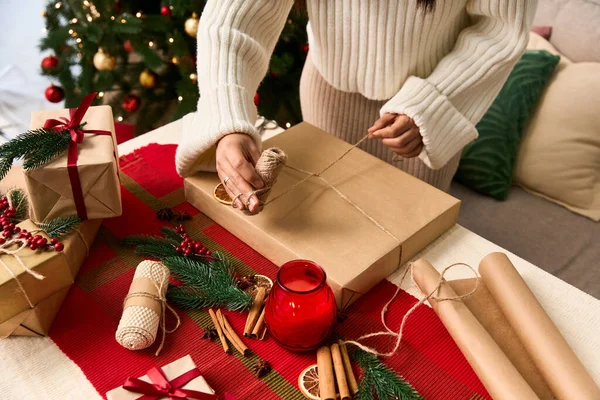 Celebrando el espíritu navideño envolviendo regalos con cuidado y decoraciones festivas cerca. - foto de stock
