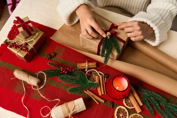 Mãos habilmente embrulhe presentes de férias cercados por decorações alegres e aromas sazonais. — Fotografia de Stock