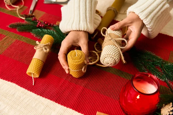 As mãos preparam velas naturais em uma mesa acolhedora decorada para uma reunião de Natal alegre. — Fotografia de Stock