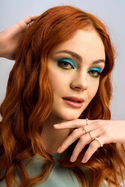 Uma jovem ruiva com maquiagem marcante posa confiantemente em um estúdio brilhante. — Fotografia de Stock