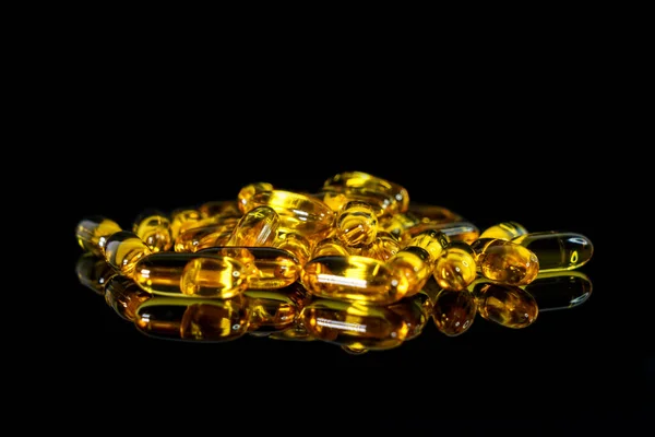 Fish oil capsules on a black background. Theme of health — Stock Photo, Image