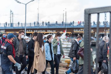 Korunaklı yüz maskeleri takan kimliği belirsiz Türkler, Coronavirus COVID-19 salgınında Emionu İskelesi 'ne demir attı. İstanbul, Türkiye. 16 Kasım 202