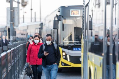 Korunaklı yüz maskesi takan kimliği belirsiz Türkler, Coronavirus COVID-19 salgını sırasında otobüslere binmek veya çıkmak için harekete geçtiler. İstanbul, Türkiye. 16 Kasım 202