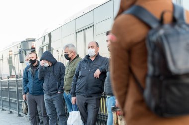 Korunaklı yüz maskesi takan kimliği belirsiz Türkler, Coronavirus COVID-19 salgını sırasında otobüslere binmek veya çıkmak için harekete geçtiler. İstanbul, Türkiye. 16 Kasım 202