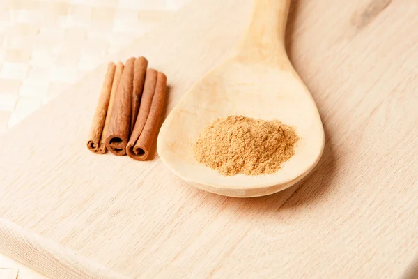 Paus de canela e pó de canela em uma colher de madeira — Fotografia de Stock