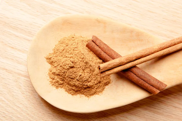 Cinnamon sticks and cinnamon powder on a wooden spoon — Stock Photo, Image