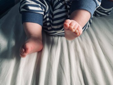 Küçük çocuk, küçük ayaklar, çoraplar yok, küçük parmaklar, yatakta oynamak, mavi