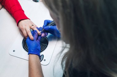 Güzellik salonunda manikür yaparken. Bir kadın tırnakları için manikür yaptırır. Güzellik uzmanı müşterilere oje sürüyor