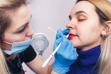 Güzellik uzmanı dudakları kalıcı makyaj için hazırlar, model aynaya bakar..