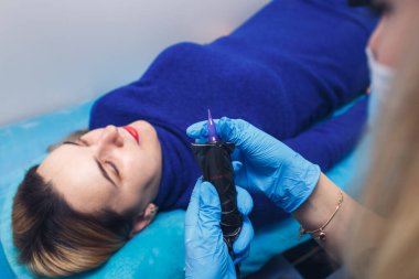 Güzellik uzmanı kozmetik uzmanı kalıcı makyaj dudakları için kalem makinesi hazırlıyor..