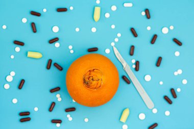 Uyuşturucu ve tümörlerin cerrahi tedavisi kavramı. Neşter, ilaçlar ve neoplastik hastalıklara örnek olarak geniş göbekli bir portakal. Hemoroit tedavisi