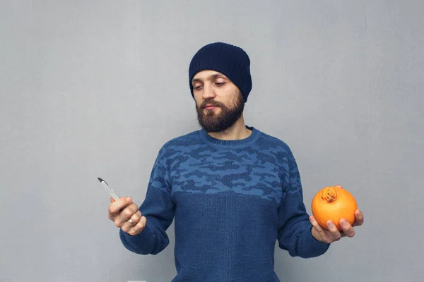 man thinks about hemorrhoid surgery. a guy holding a scalpel and an orange.