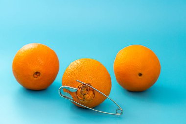 Mavi arka planda çirkin ve normal portakallar. Hemoroit ağrısının sembolü olarak iğneyi tak.