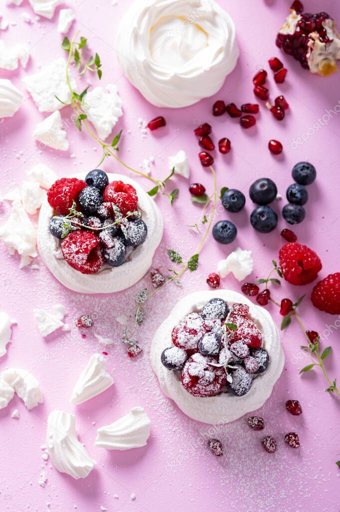 Pavlova meringue cake with berries on dusted sugar pink background