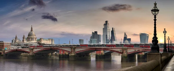 伦敦黑弗里斯桥上穿越泰晤士河的红色双层客车全景 背景为伦敦金融城 免版税图库图片