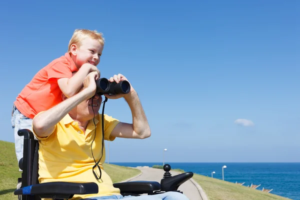 Le père et le fils handicapés jouent avec les jumelles — Photo