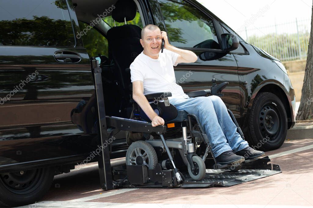 Disabled man on wheelchair standing on the car lift