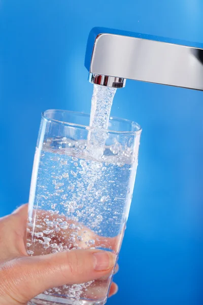 Llenando un vaso de agua. Fondo azul . —  Fotos de Stock