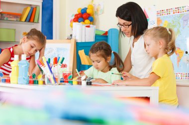 Children with teacher draw in the classroom clipart