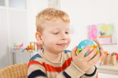 Preschooler in the classroom holds  a globe