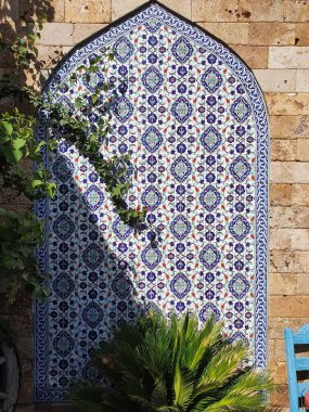 Boyanmış kiremitlerle duvar süslemesi. Asyalı gibi boyanmış, mavi bir tonda..