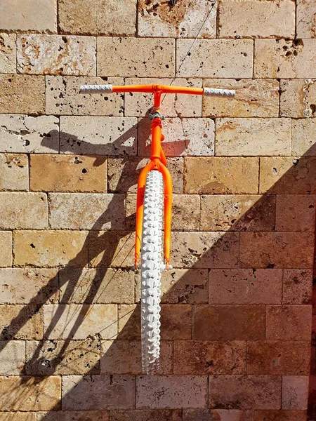 Taş bir duvarda turuncu bisiklet. Binanın taş duvarının güzel dekorasyonu..