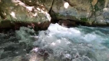 Yerden fışkıran bir su akıntısı. Nehrin kaynağı kayalar ve taşlar arasında başlar..