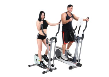 genç kadın ve erkek üzerinde eliptik çapraz eğitmen egzersizleri yapıyor