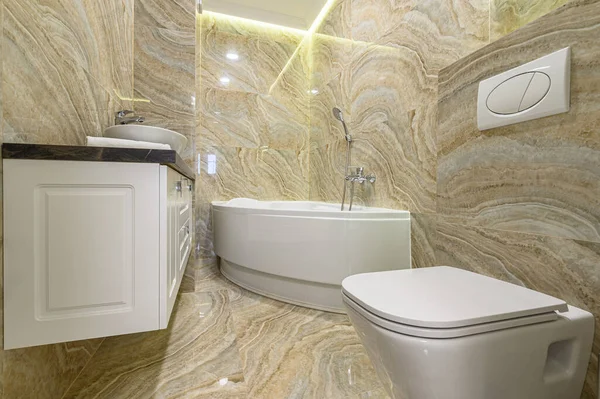 Роскошная ванная комната с белой ванной и бежевой мраморной плиткой — стоковое фото