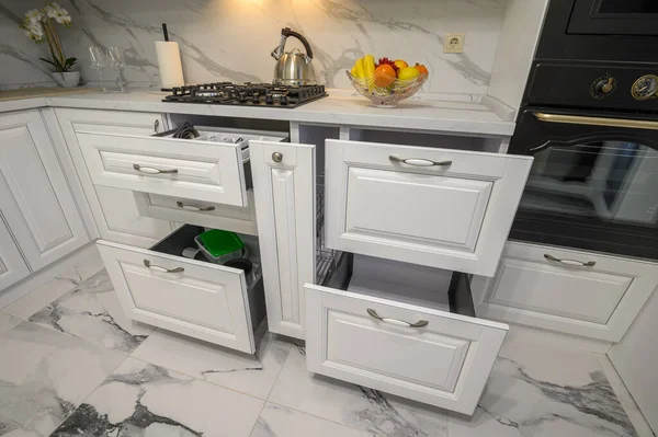 Open drawers with kitchenware at modern white kitchen